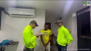 Martha Mancera, Fiscal Mancera, Fiscal Martha Mancera En la fotografía aparece un hombre de pie, delgado, moreno, con los brazos hacia adelante, esposado, vestido de camiseta amarilla y pantalón blanco, acompañado de dos uniformados de la Policía Nacional.