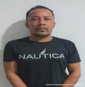  En la imagen aparece el rostro de frente de un hombre trigueño, con ligera barba, vestido con camiseta negras y letras blancas.