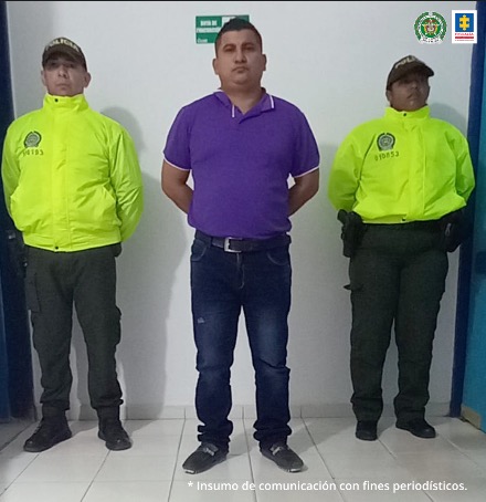 En la fotografía se observa la imagen de un hombre con camiseta morada pantalón negro custodiado por dos agentes de la Policía Nacional.