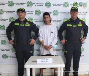 En la fotografía aparece un hombre de pie, joven, piel trigueña, cabellos negros, vestido de buzo blanco, custodiado por dos uniformados de la Policía Nacional. Delante de ellos hay una mesa donde está el arma blanca que se le incautó.