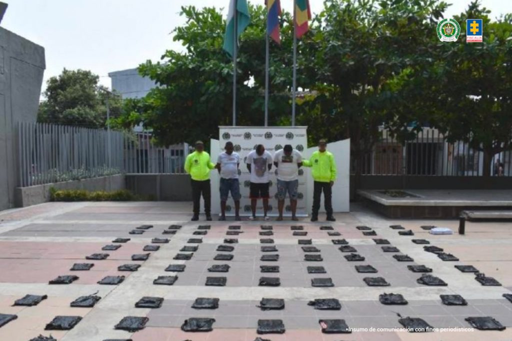 Martha Mancera, Fiscal Mancera, Fiscal Martha Mancera En la fotografía están tres hombres de pie, moreno, gruesos, vestidos con camisetas blancas y bermudas azules, custodiados por dos uniformados de la Policía Nacional. Delante de ellos se ven la droga incautada en paquetes rectangulares.