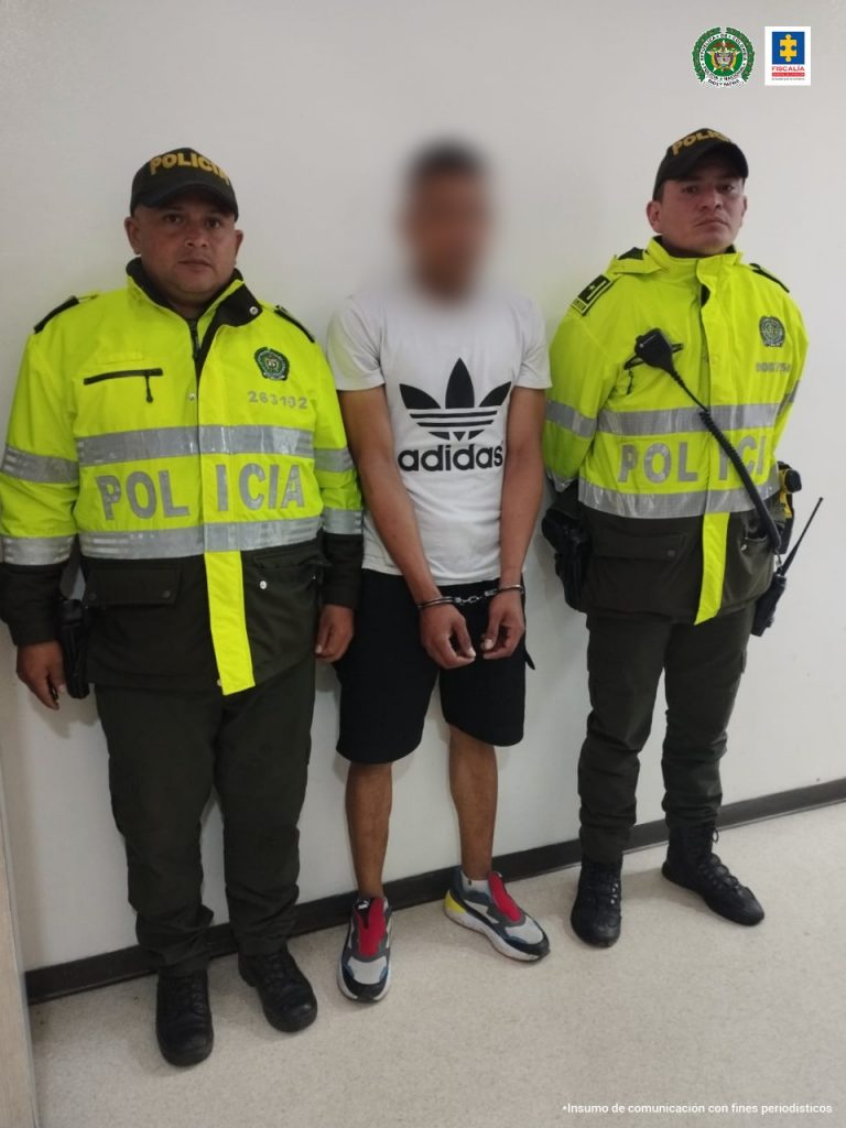 En la imagen se observa a un hombre de camiseta blanca, bermuda negra custodiado por dos agentes de la Policía nacional.