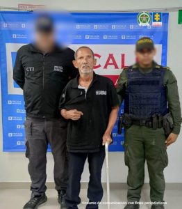 Asegurado adulto mayor señalado de abusar sexualmente de un paciente en un hospital de Cartagena 1 En la fotografía está un hombre trigueño, delgado, de avanzada edad, de pie sosteniéndose con un bastón plateado, vestido con camiseta y pantalón negro, custodiado por un uniformado del CTI y de la Policía Nacional.