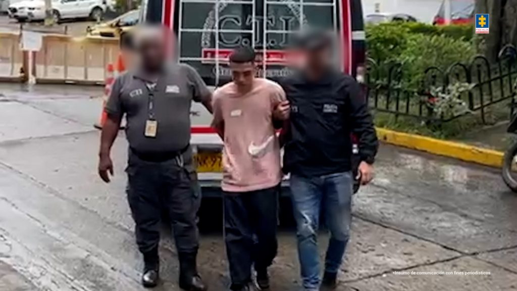 Róbinson Suárez Suárez, alias Chispún La fotografía está tomada en exteriores y aparece en acción de caminata, con los brazos atrás Róbinson Suárez Suárez, alias Chispún. Viste con Camisa de color rosado y manga corta; pantalón de sudadera de color negro y zapatillas negras. A sus extremos hay servidores del CTI de la Fiscalía. Detrás de ellos hay un vehículo con el logo del CTI de la Fiscalía.