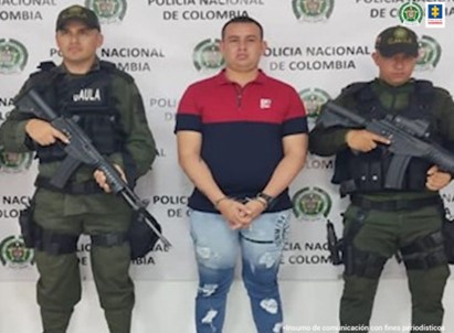 En la fotografía aparece el capturado, junto a dos uniformados del Gaula de la Policía Nacional, en la parte de atrás se observa el banner de la Policía Nacional