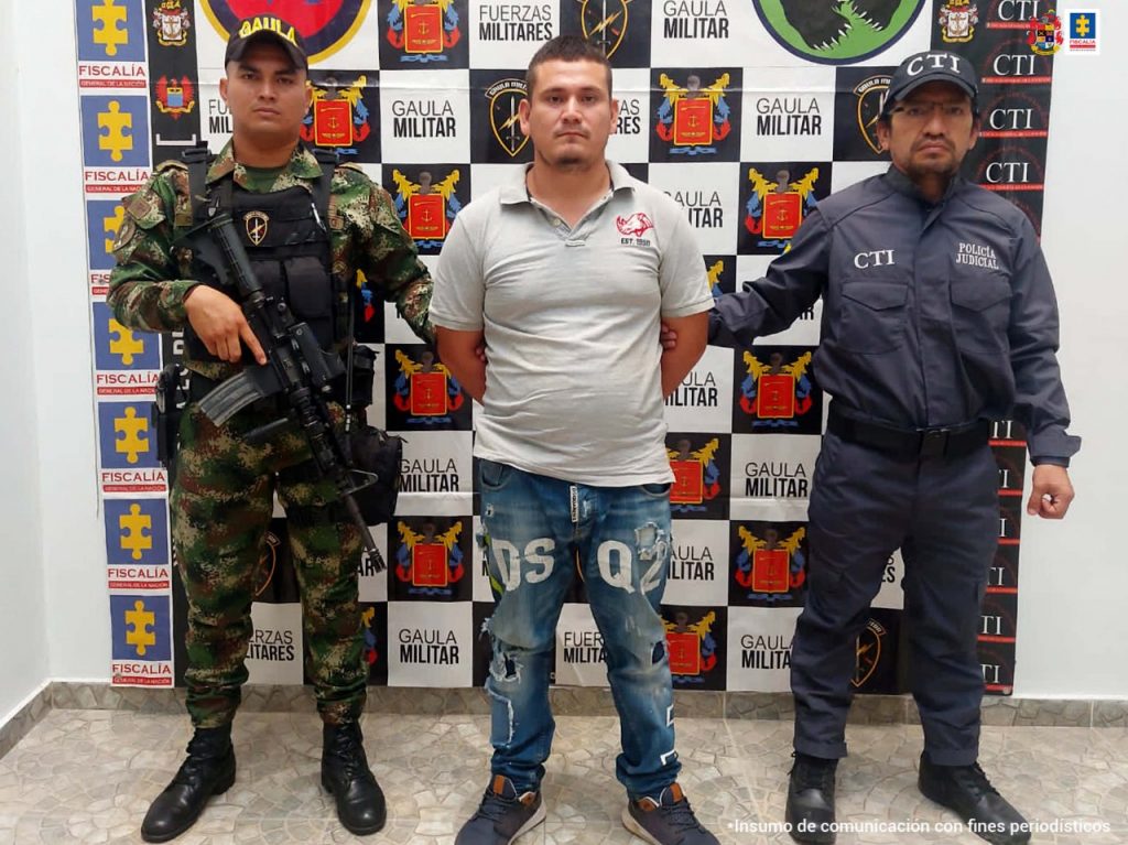 En la fotografía aparece un capturado, junto a personal de CTI y Ejército Nacional. En la parte posterior de la imagen se ven banners de Ejército Nacional y la Fiscalía General de la Nación.   