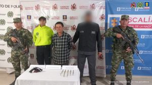  En la fotografía está el procesado con un servidor del CTI, uno de la Policía y dos del Ejército Nacional, y una mesa adelante con arma de fuego y varias municiones