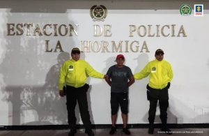 En la fotografía aparece un capturado, junto a personal de Policía Nacional. En la parte posterior de la imagen se ven banners de Policía Nacional y Fiscalía General de la Nación.