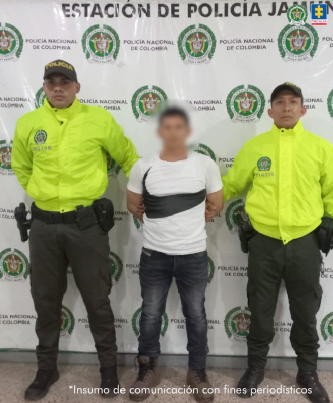 En la fotografía se aprecia de pie y con los brazos atrás a Gerdmuller Constantino García Cabrera. Viste con camiseta de manga corta de color blanco, con franja negra irregular a la altura del pecho; jean azul oscuro  y botas marrón con cordones negros. A sus extremos hay uniformados de la Policía Nacional. Detrás de ellos hay un pendón institucional de la Policía.