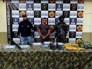  En la imagen está alias Andrés con un servidor del CTI y Ejército Nacional y  una mesa con las armas, municiones, radios de comunicación y demás elementos incautados
