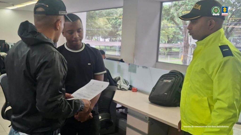 La fotografía fue tomada dentro de unas oficinas y se aprecia de pie y con los brazos adelante a Gilmar Steven Portocarrero Mosquera. Viste camiseta de manga corta, de color negro, con rebetes blancos en cuello y mangas; asimismo, pantalón negro. Al extremo derecho de él hay un servidor del CTI de la Fiscalía quien tiene un documento en sus manos. Al lado izquierdo un uniformado de la Policía Nacional.