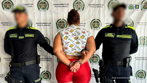 Se observa a la capturada de espaldas junto a dos uniformados de la Policía Nacional. Detrás se observa el banner de la Policía Nacional.