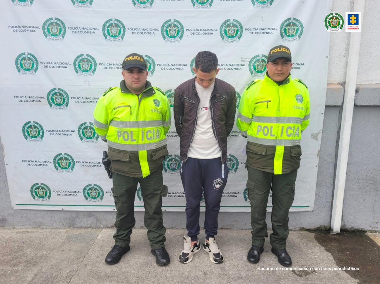 El hombre quien fue capturado en Bogotá se encuentra esposado, en compañía de dos uniformados de la Policía Metropolitana de Bogotá.
