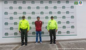  en la imagen se ve una persona detenida bajo custodia de dos policías.