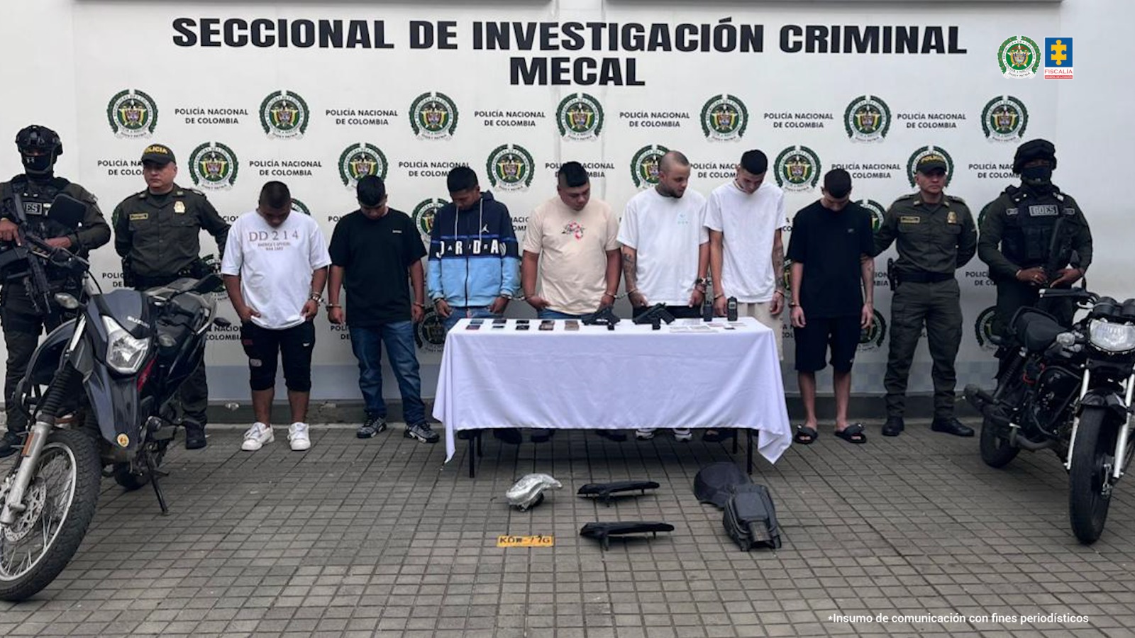En la fotografía se aprecian de pie, en hilera y esposados entre sí, ‘Los de La Quinta’. A sus extremos hay uniformados de la Policía Nacional. Delante de ellos hay una mesa con mantel blanco y sobre ella se ven dos armas de fuego, varios celulares, radios de comunicación y documentos. En el piso hay partes de motocicletas. Y a los extremos hay dos motocicletas. Detrás de ellos hay un pendón institucional de la Policía.