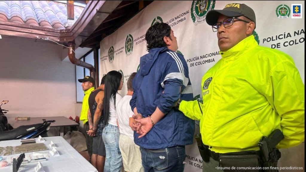 en la foto aparecen cuatro de los capturados, siendo custodiados por dos policías.