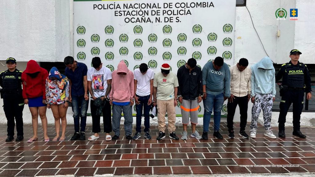 Se visualiza a los capturados junto a uniformados de la Policía Nacional. Detrás de ellos el banner que identifica a la Policía Nacional