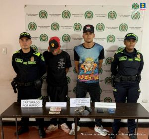 En la fotografía se aprecian de pie y con los brazos atrás a Guillermo Antonio Hurtúa Aguiar y Jefferson Andrés Jaramillo Bohórquez. Uno de ellos viste con gorra de color rojo y negro, camiseta de manga corta y pantalón de color negro; zapatillas blancas. El otro vista gorra negra, camiseta de manga corta negra con estampado de color en la parte frontal, pantalón negro y zapatillas blancas. A los extremos de ellos hay uniformados de la Policía. Delante de ellos hay una mesa de color marrón y sobre ells se aprecia dinero en efectivo, una arma de fuego y dos teléfonos celulares. Asimismo, cuatro letreros que dicen: ‘Capturado por hurto’, ‘Dinero incautado’; ‘Fabricación, tráfico y porte ilegal de armas de fuego o municiones’, ‘Celular incautado’. Detrás de ellos hay un pendón institucional de la Policía.