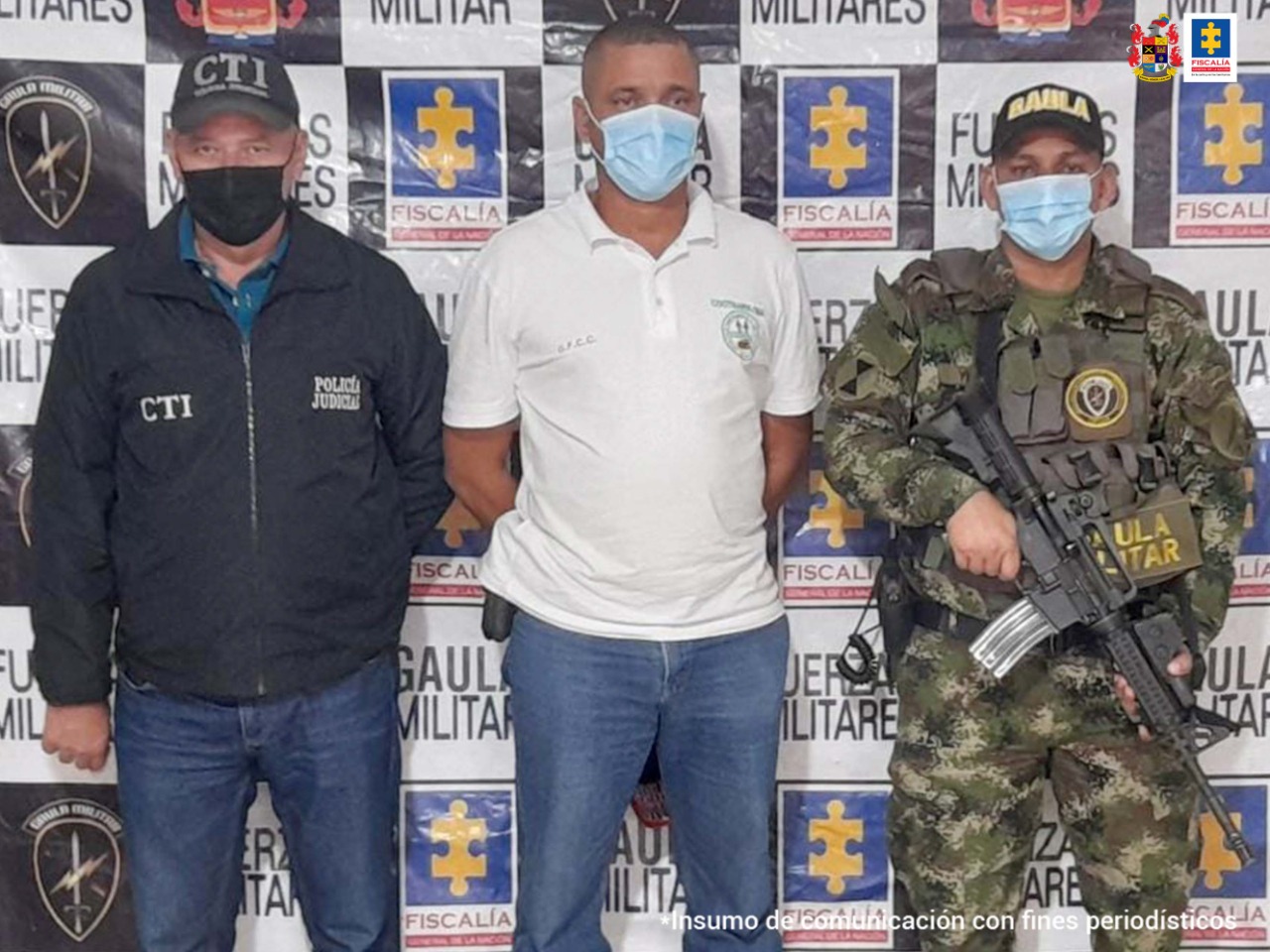 Un hombre vestido de blanco y con tapabocas, aparece capturado en medio de personal del CTI y de la Fiscalía y el Ejército.