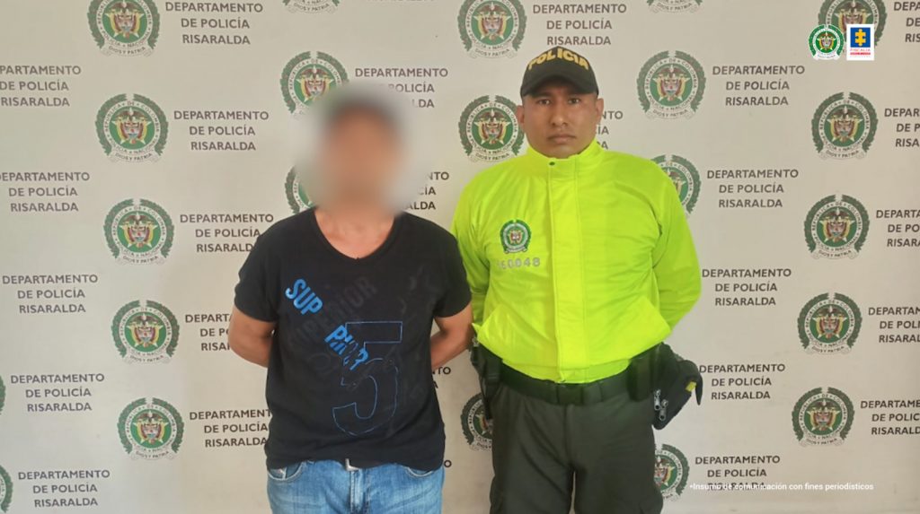 En la tercera fotografía se observa a un capturado, masculino, y a un costado, funcionario de Policía Nacional. Atrás pendón de Policía Nacional