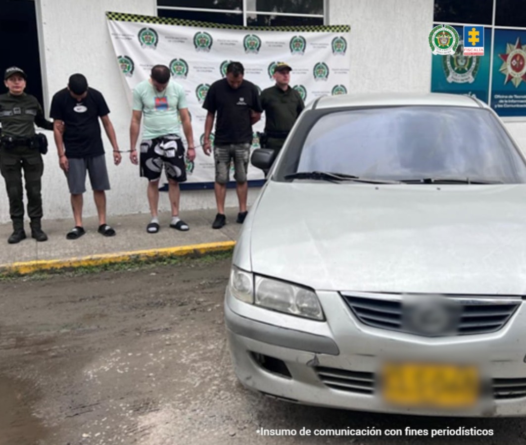 En la fotografía se aprecian de pie, con la cabeza agachada y esposados entre sí a Heiner Cáceres Tapasco, Jan Michael Gabriela Medina, Brayan Steven Bedoya Enríquez. Uno viste camiseta de color negro, mangas cortas; bermuda gris oscuro y pantuflas negras. Otro viste camiseta de color verde claro con estampado en el pecho, bermuda negra con estampados blancos y grises, medias grises y pantuflas negras. un tercero viste con camiseta de color negro y manga corta, bermuda de color gris desgastada y zapatos negros. A sus extremos hay uniformados de la Policía Nacional. Al lado derecho de la fotografía hay un vehículo gris y detrás de ellos hay un pendón institucional de la Policía.