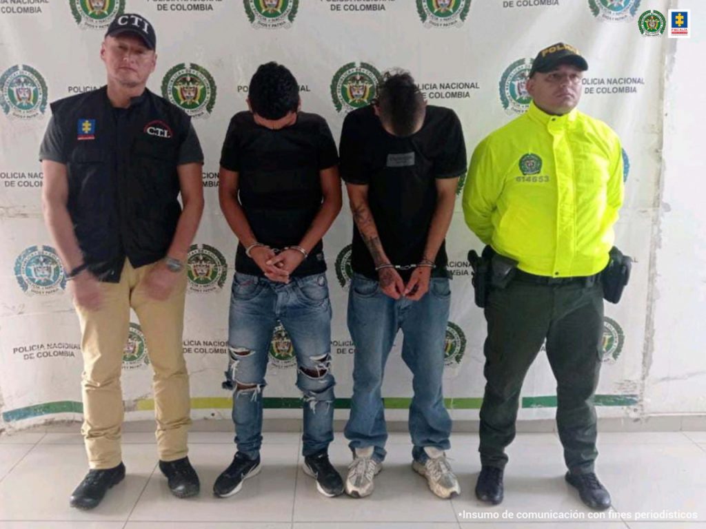 En la foto aparecen, de pie, con los brazos adelante y esposados, Francisco Javier y Juan Sebastián Posso Parra. Ambos visten camiseta de manga corta oscura y jean azul. Al lado derecho de ellos hay un servidor del CTI de la Fiscalía y al lado izquierdo de ellos hay un uniformado de la Policía Nacional. Detrás de ellos hay un pendón institucional de la Policía.