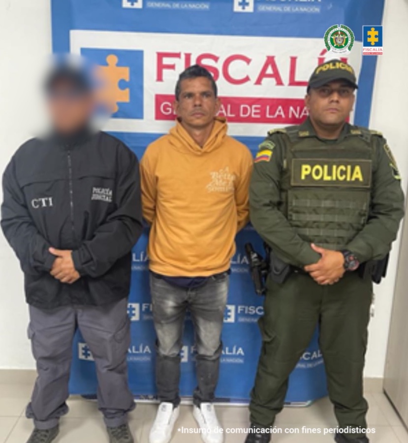 En la fotografía se aprecia de pie y con los brazos atrás a Hernando de Jesús Suárez Hernández. Viste buso amarrillo mostaza, de manga larga; pantalón gris desgastado y zapatillas blancas. A su lado derecho hay un servidor del CTI de la Fiscalía y a su izquierda un uniformado de la Policía Nacional. Detrás de ellos hay un pendón institucional de la Fiscalía.