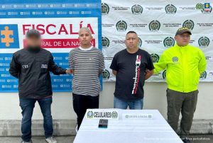 En la fotografía aparecen los dos capturados junto a un funcionario del CTI y un integrante de la Policía Nacional. En la parte superior está un banner de la Policía Nacional.