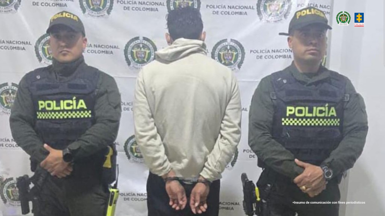 El capturado se encuentra de espalda y custodiado por dos uniformados de la Policía Nacional. En la foto se ve de fondo un backing de la Policía Nacional.