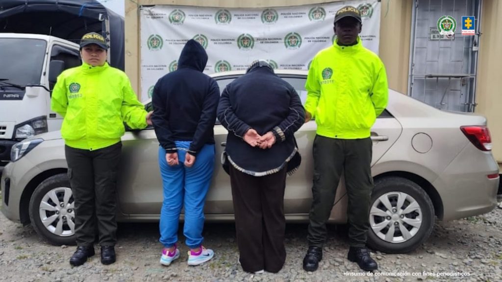 En la fotografía aparecen las dos mujeres capturadas junto a dos agentes de la Policía Nacional. En la parte superior se observa un banner de la Policía Nacional