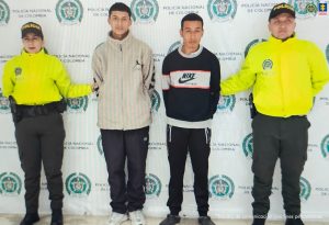 En la foto aparecen los capturados junto a dos agentes a la Policía Nacional. En la parte superior está un banner de la Policía Nacional