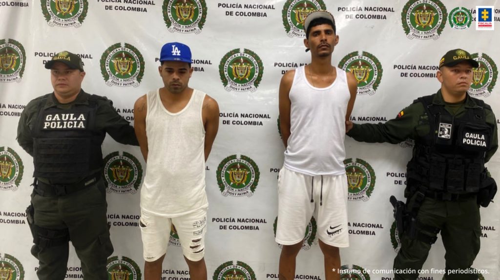 En las fotografías aparecen los 4 presuntos miembros de la banda Los Shottas junto a agentes de la Policía Nacional. En la parte posterior se ve un banner de la Policía Nacional.