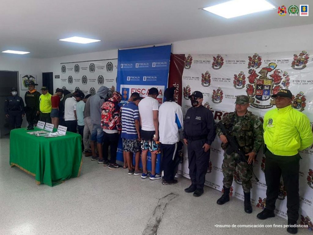 En la foto aparecen los 12 capturados de espalda, custodiados por miembros de la Policía Nacional y el Ejército. 