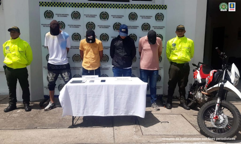 en la foto se aprecian los cuatros asegurados siendo custodiados por dos miembros de la Policía . 