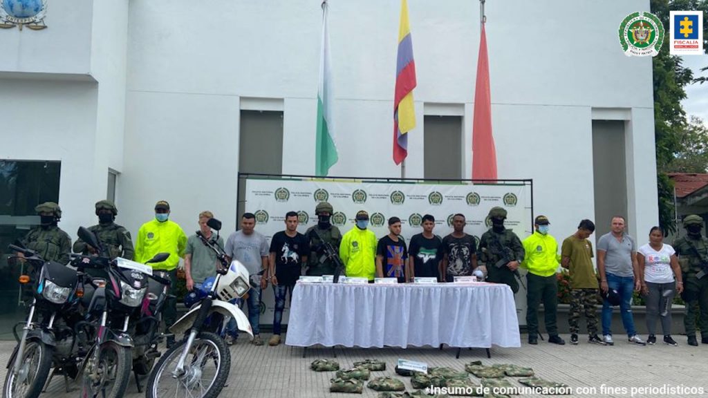 En la imagen se encuentran 9 de los capturados en fila, con 3 motocicletas incautadas y varios uniformados de la Policía Nacional.