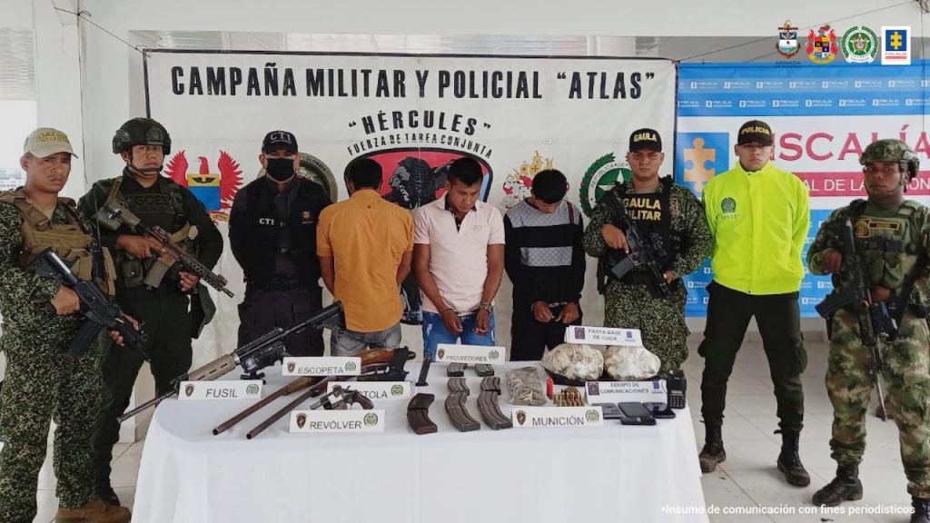 En la fotografía aparecen tres hombres capturados, uno de ellos de espaldas, junto a dos agentes de la Policía Nacional y unidades del Gaula Militar, la Armada y el Ejército Nacional. En la parte posterior de la imagen se ve un banner de la Fiscalía General y la Fuerza de Tarea Hércules.