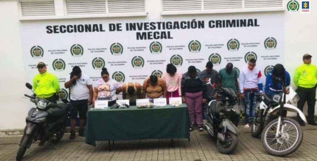 En la fotografía se observan los 15 capturados junto a dos agentes de la Sijin de la policía metropolitana. En la parte posterior se observa una mesa con estupefacientes, drogas, armas, dinero, entre otros elementos.