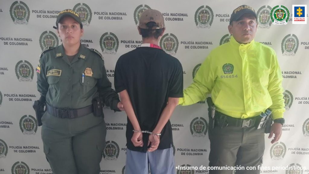 el capturado de espaldas custodiado por dos uniformados de la Policía