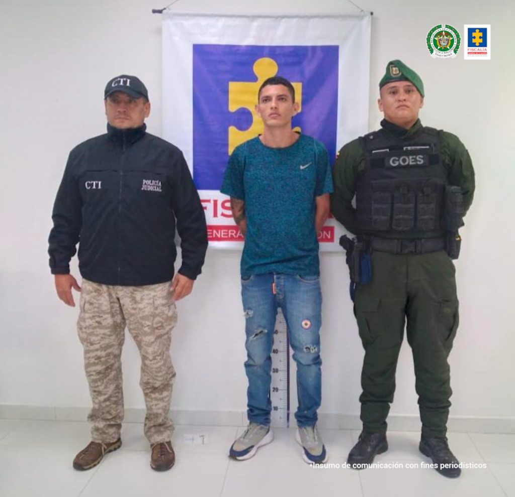capturado custodiado por investigador del CTI de la Fiscalía y un policía. Detrás pendón de la Fiscalía.