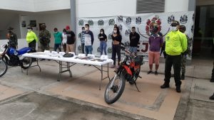 Los capturados aparecen detrás de una mesa, donde se exhiben los estupefacientes y elementos incautados.
