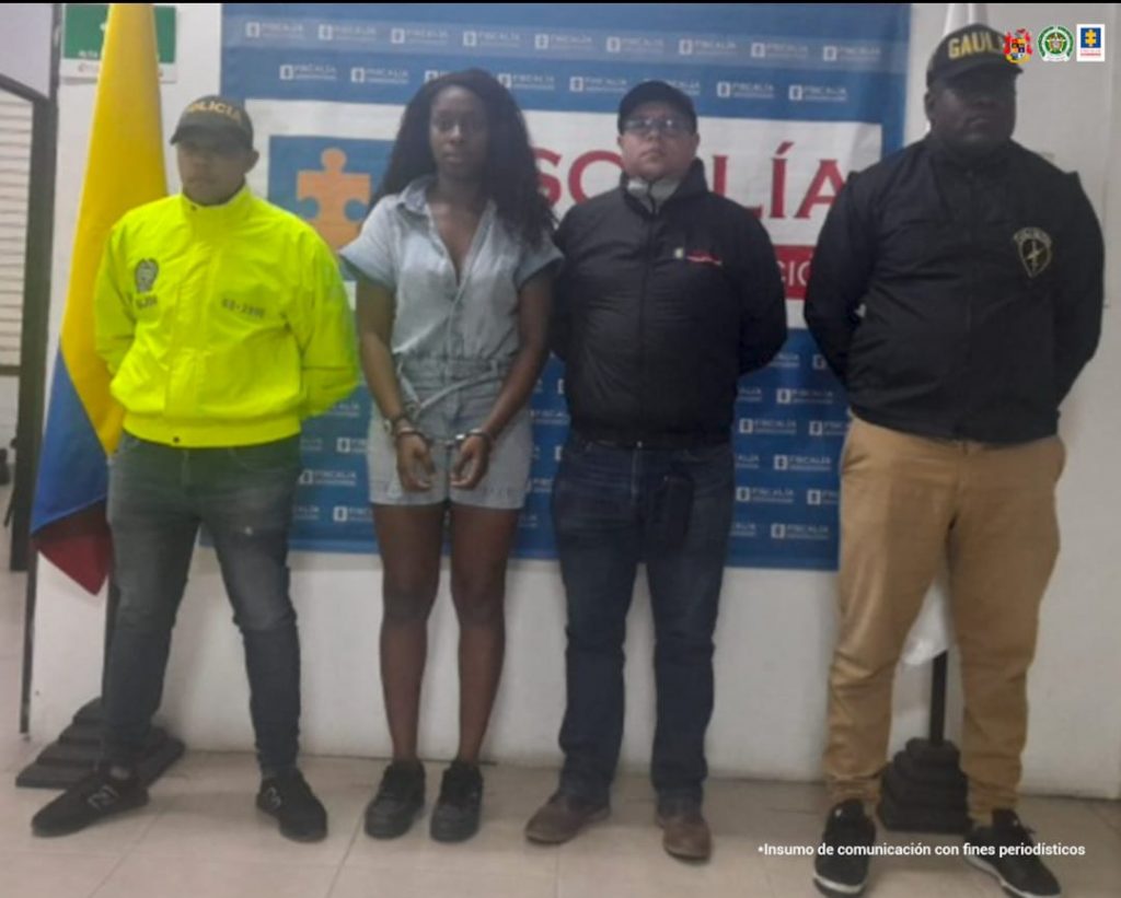En la fotografía aparece la capturada junto a un servidores del CTI, un agente de la Policía Nacional y un integrante del Gaula Militar.  En la parte superior está un banner de la Fiscalía Nacional. 