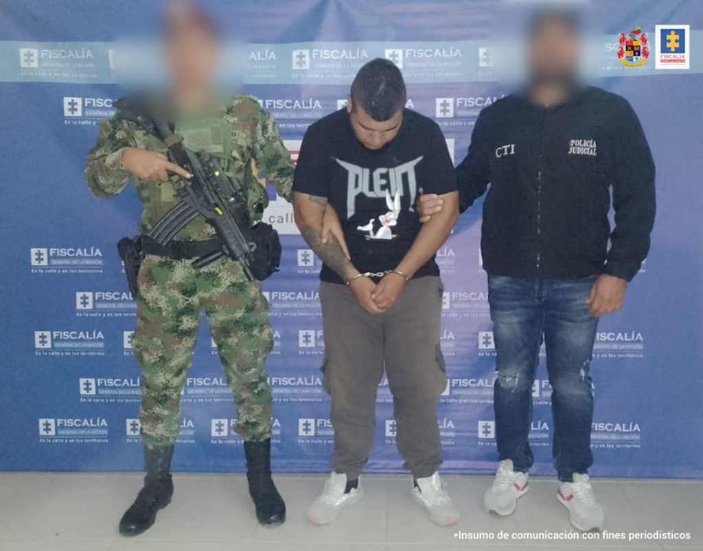 En la fotografía aparece el capturado junto a un servidor del CTI y un soldado del Ejército Nacional. En parte superior está un banner de la Fiscalía General de la Nación
