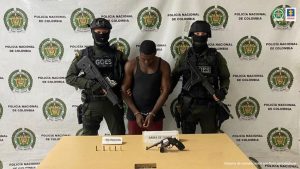 En la fotografía aparece el capturado junto a dos agentes del Goes de la Policía Nacional. En la posterior está una mesa con una pistola calibre 38 y munición 