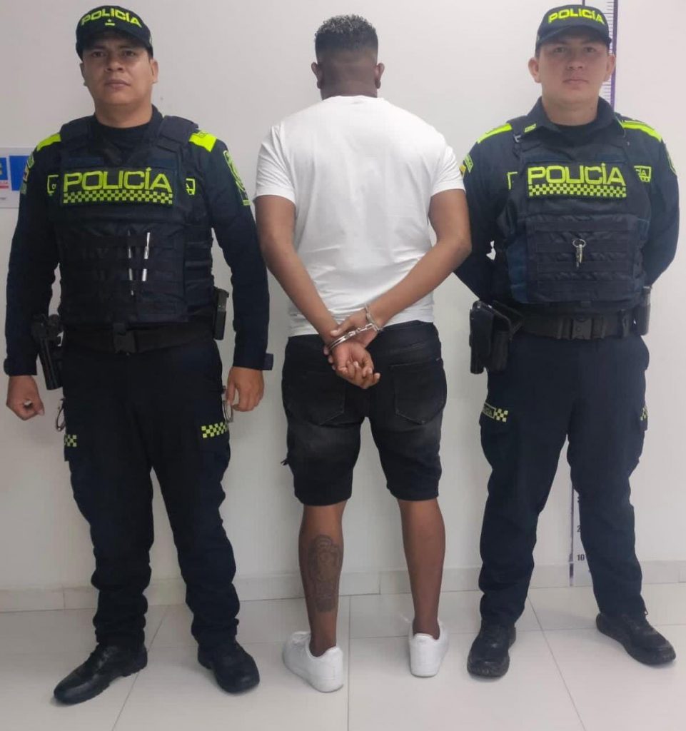 capturado de espaldas custodiado por dos policías.