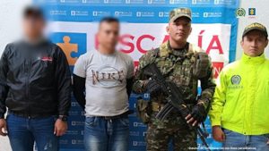 En la imagen se ve una persona detenida bajo custodia de un investigador del CTI, un integrante del Ejército y de la Policía. Detrás suyo un backing institucional.