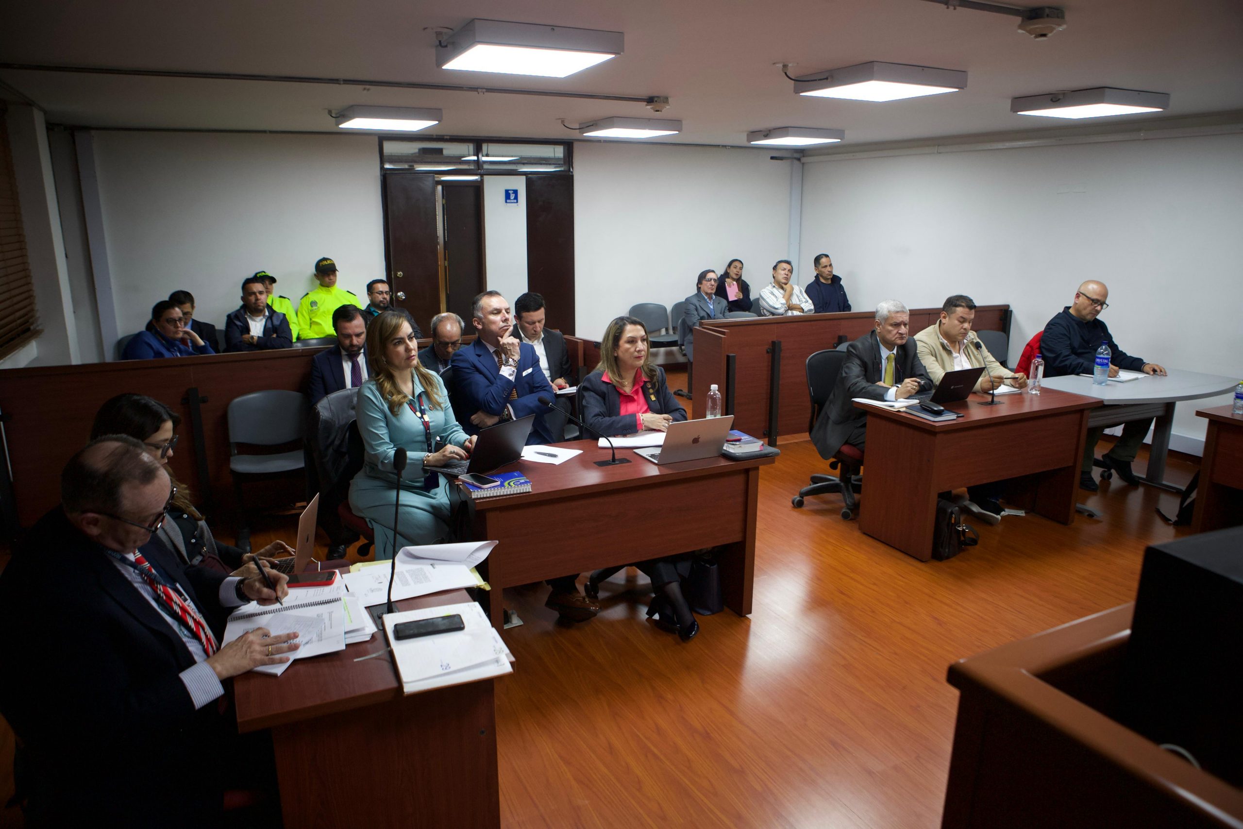 En la fotografía se visualiza un grupo de 20 personas en la audiencia pública en donde estan los implicados, abogados, acompañantes y funcionarios de la policía