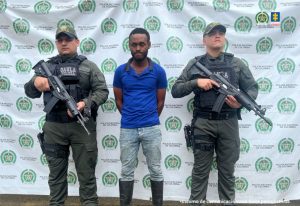 En la foto aparece Leyson Chaverra Blandón a quien capturaron por los delitos de extorsión y terrorismo acompañado por dos funcionarios de la Policía Nacional.
