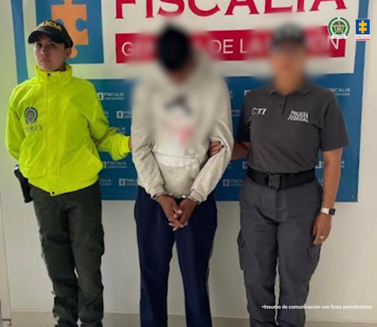 El hombre aparece en el centro de la imagen, esposado y con las manos al frente. A un costado está un miembro de la Policía y al otro un miembro del CTI de la Fiscalía 