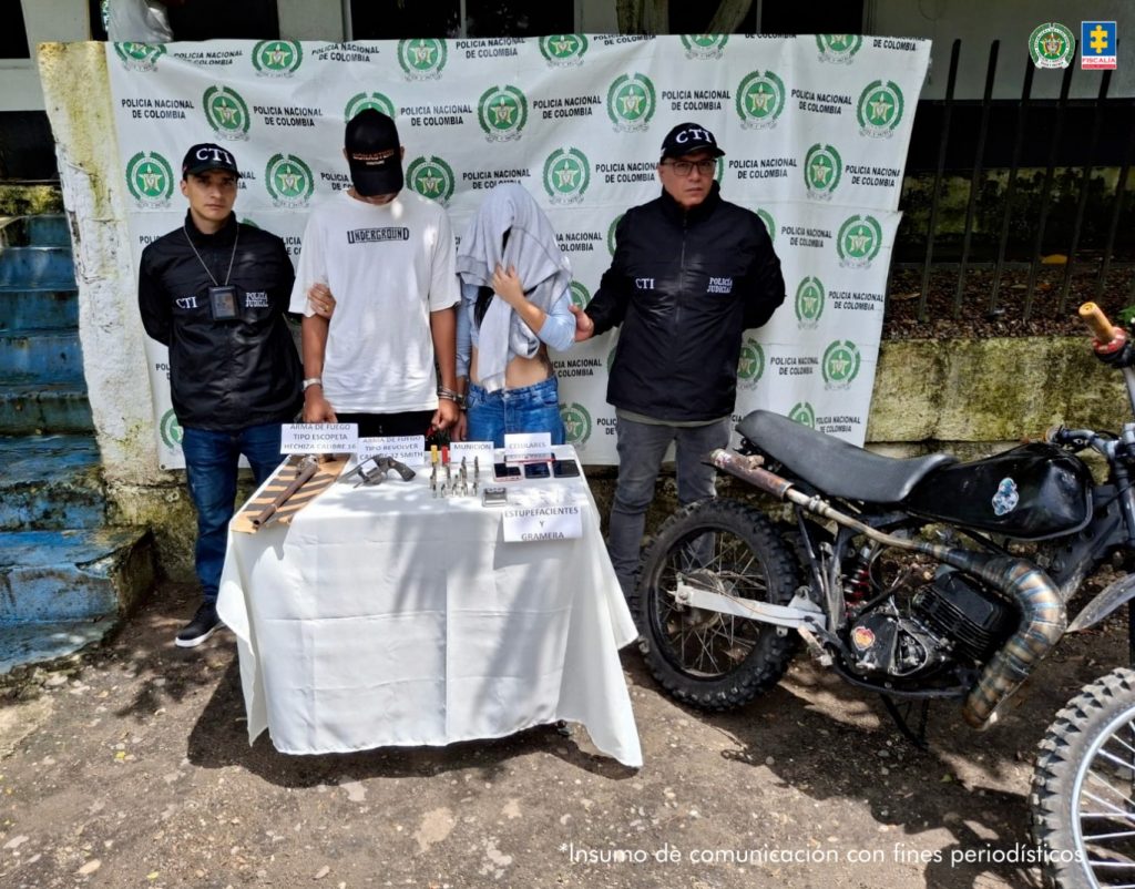 Durante diligencias de registro allanamiento en el barrio Victoria Real de La Dorada fueron capturados Marlon Exneider Ortiz Molina y Yulieth Liceth Ordoñez Rojas. Un juez los envió a la cárcel. En la foto aparecen Marlon Exneider Ortiz Molina y Yulieth Liceth Ordoñez Rojas acompañados de funcionarios del CTI a los lados y atrás un pendón con logos de la Policía.