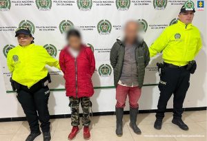 Los imputados se encuentra en custodia por dos uniformados de la Policía Nacional. Detrás hay un backing de la Policía.